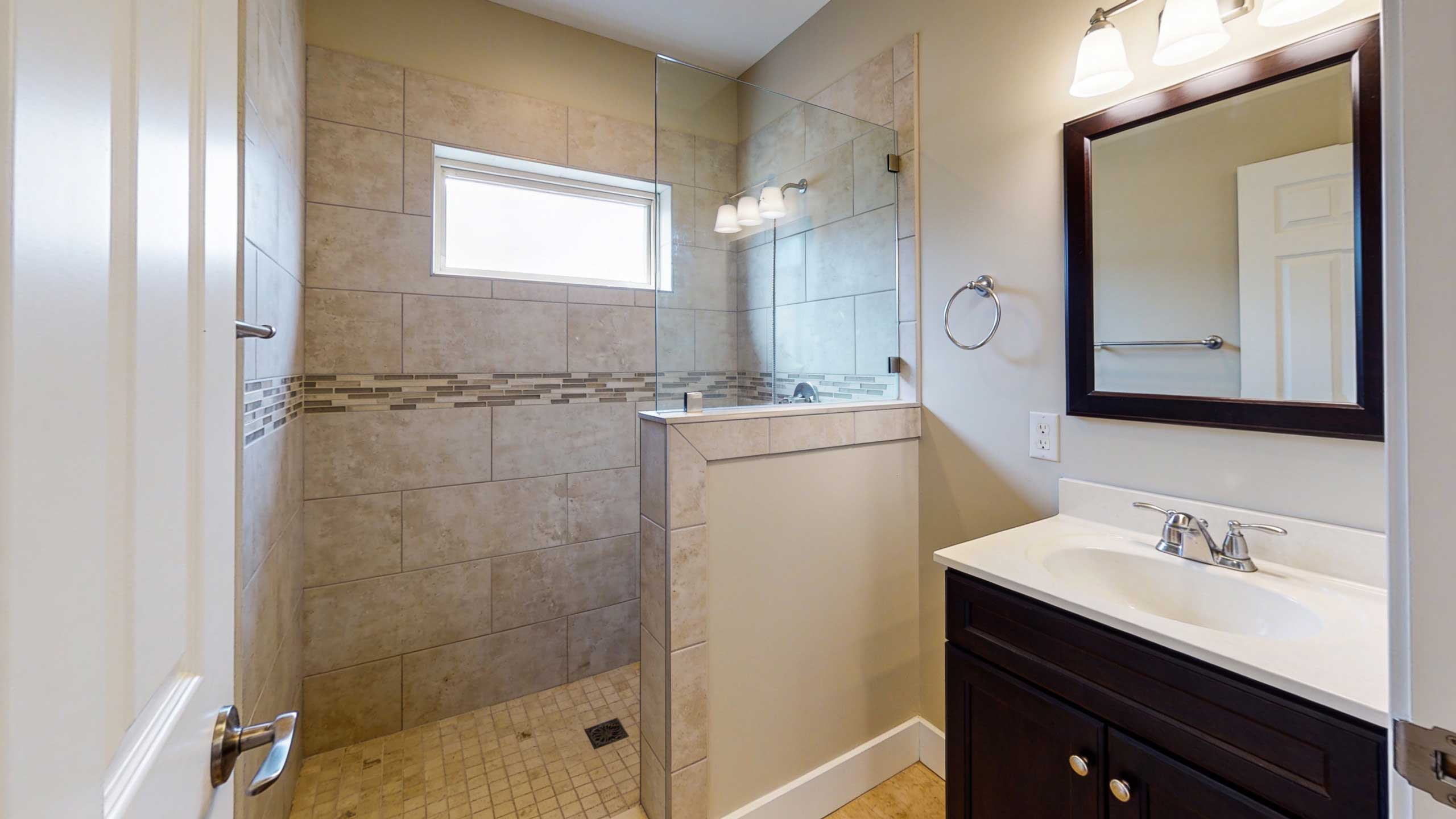 Doorless shower with a half-height privacy wall in a compact bathroom